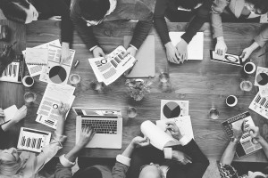 aerial shot of group of professionals collaborating in a long table, sharing documents with graphs