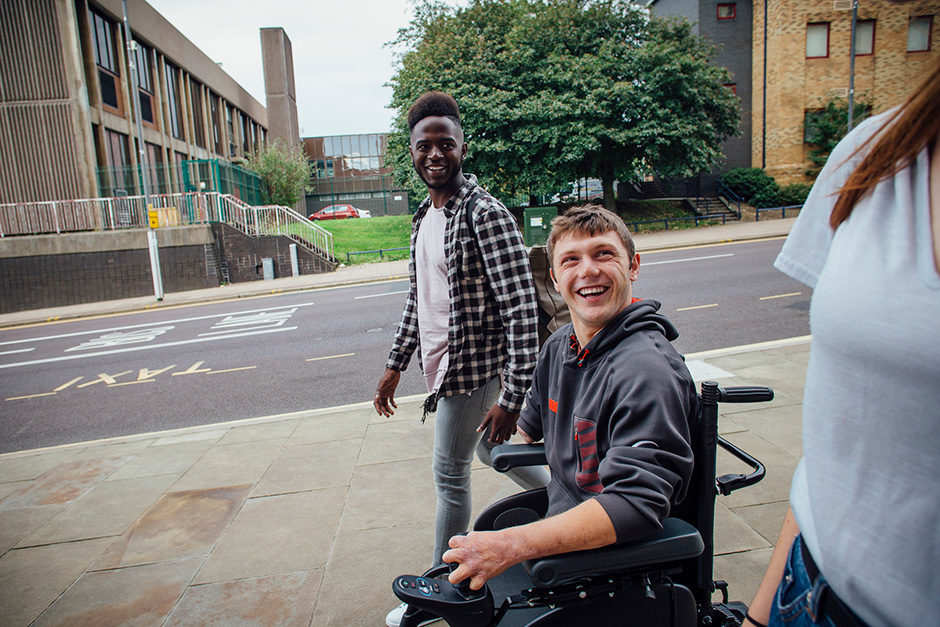 Blog featured image: a smiling young man in a power chair with his friends